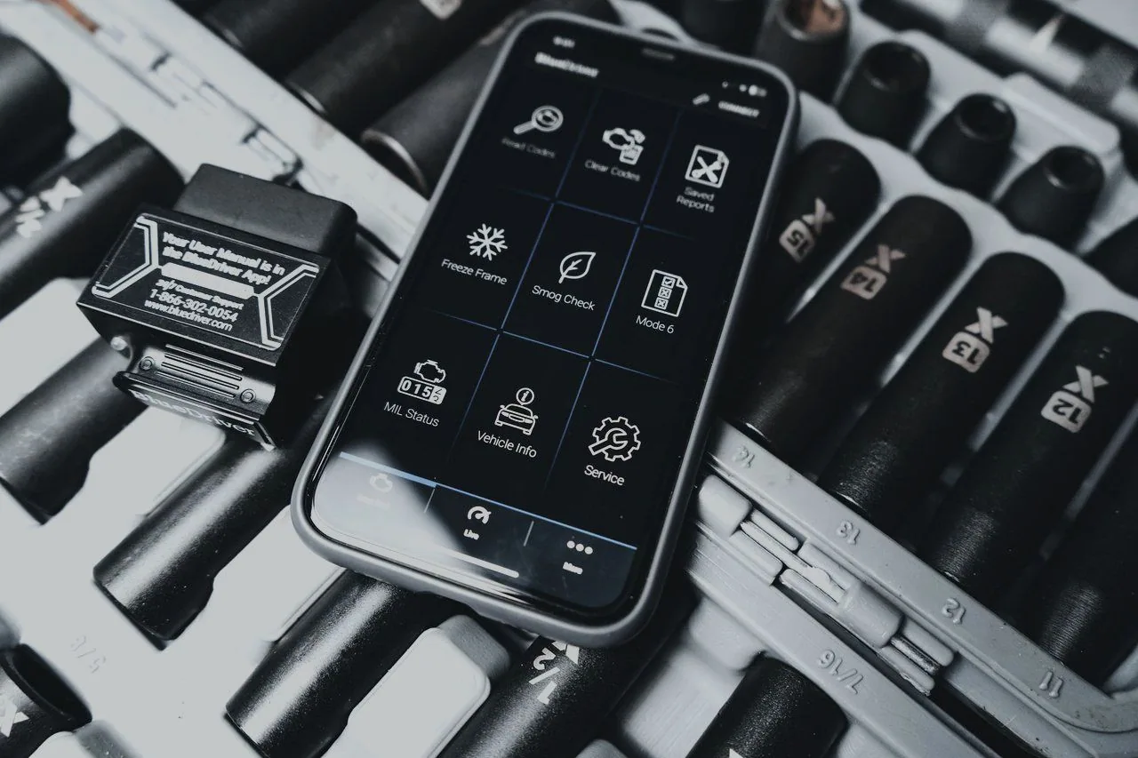 An OBD diagnostic reader and phone app beside a socket set