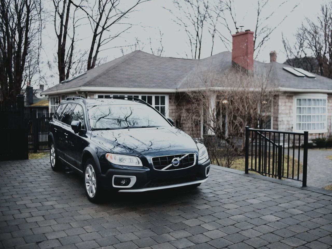 A car parked on a block-paved residential driveway outside a house