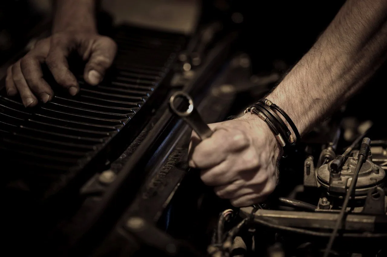 A mechanic’s hands turning a spanner deep inside an engine