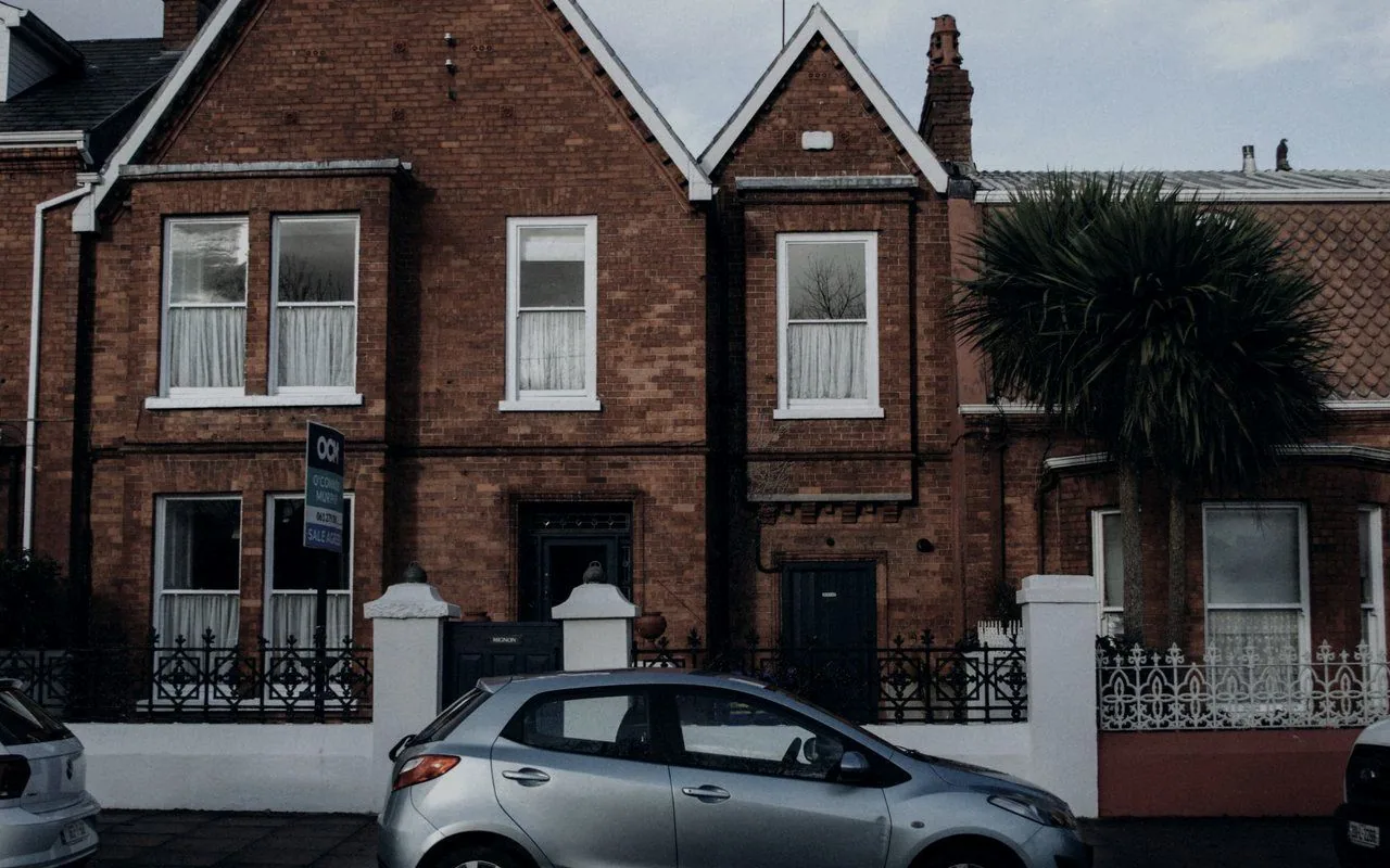 A car parked outside red-brick terraced houses on a British street