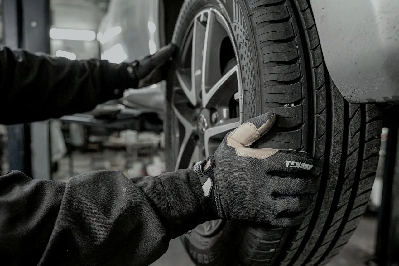 Gloved hands fitting a wheel back onto a car